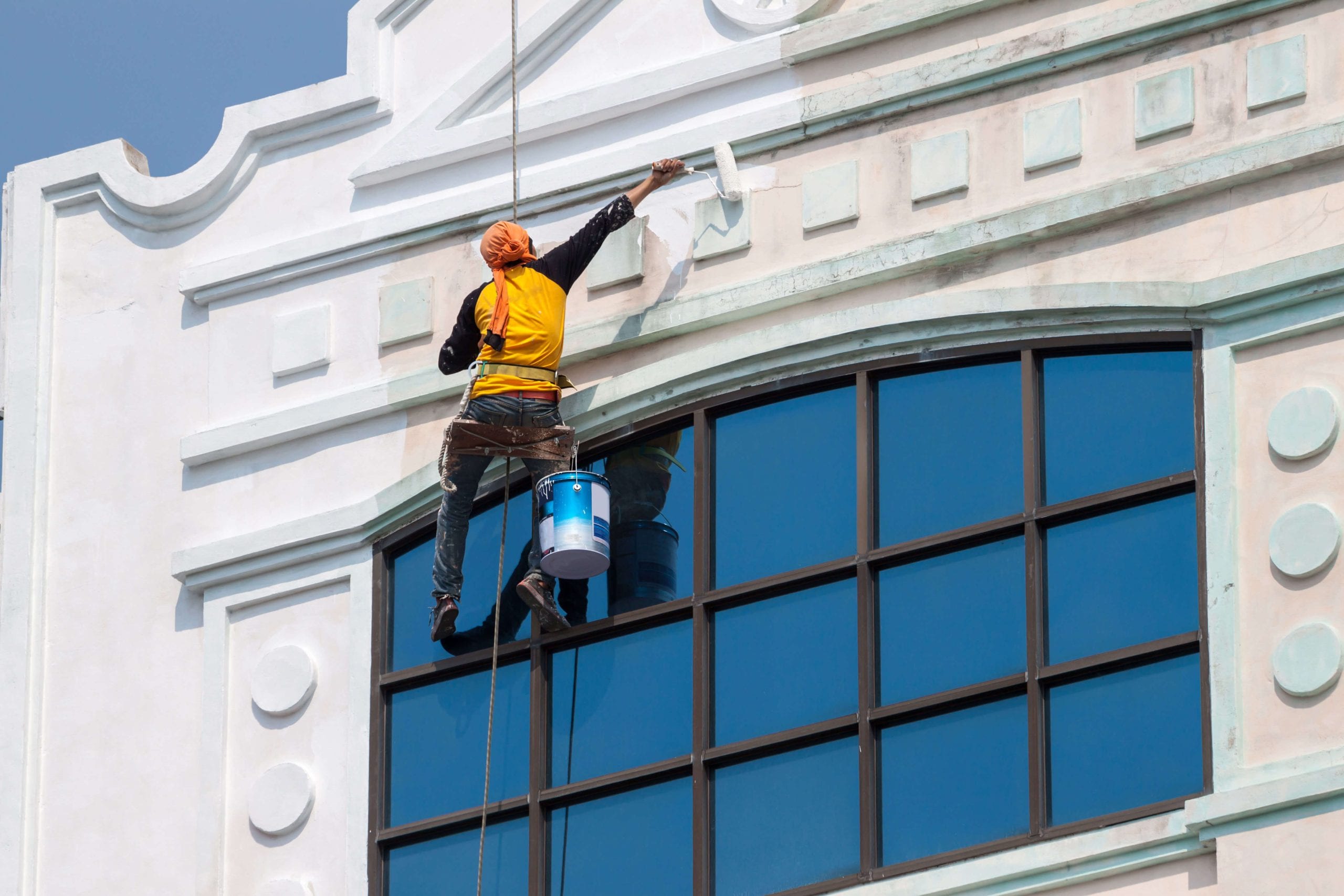 A team of professional painters working on the exterior of a commercial building in Charlotte, applying fresh coats of paint to revitalize its appearance.